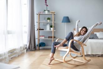 
		Junge Frau sitzt lachend auf dem Sessel
	